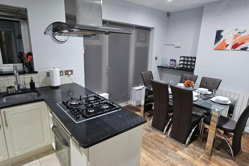 a kitchen with a stove and a table with chairs at Cozy & Elegant 4 Bedroom Home Near Wembley in The Hyde