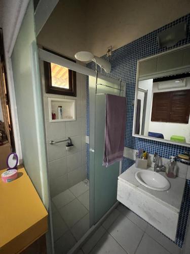 uma casa de banho com um chuveiro, um lavatório e um espelho. em Casa em Guarajuba em Camassari