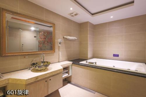 a bathroom with a bath tub and a sink at Chimei Fashion Hotel in Zhongli