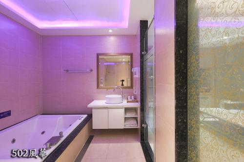 Baño púrpura con bañera y lavabo en Chimei Fashion Hotel, en Zhongli