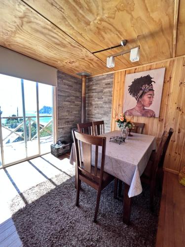 Cabañas Emma Maicolpue في أوسورنو: غرفة طعام مع طاولة مع كراسي و لوحة