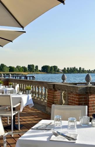 a restaurant with white tables and chairs and a body of water at Villa Pioppi Hotel in Sirmione