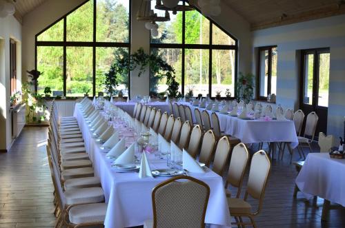 un largo salón de banquetes con mesas y sillas blancas en Zajazd Rzepicha, en Biskupice