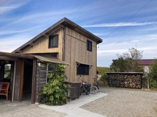 Rustic Resort Isumi / Vacation STAY 5447 في Isumi: منزل خشبي مع دراجة متوقفة أمامه