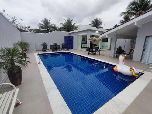 a swimming pool with a pool noodle in front of a house at Belissima casa Jardim Acapulco in Guarujá