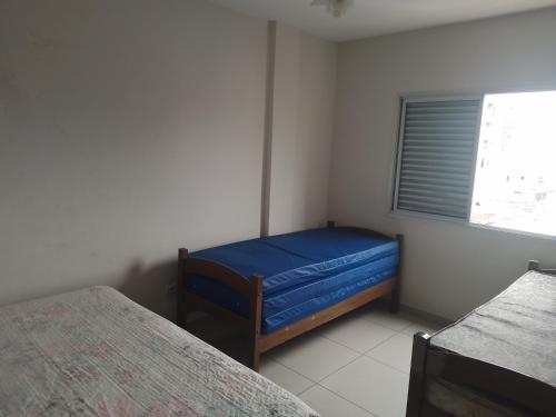 a small room with two beds and a window at Apartment Vila Tupi in Praia Grande
