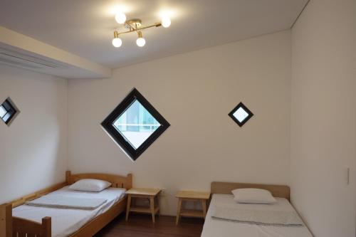 two beds in a room with a window at Mir Guesthouse in Jeju