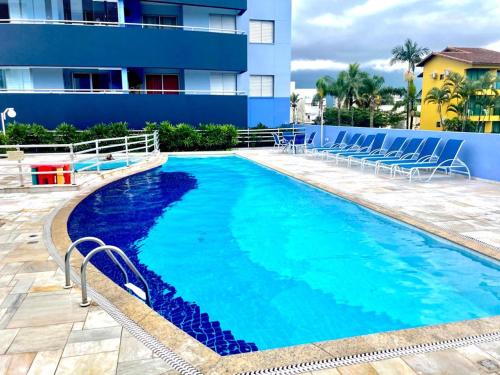 a swimming pool with chairs next to a building at Apto em Bertioga , pé na areia in Bertioga