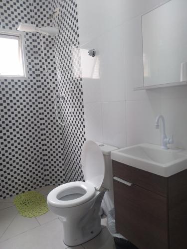 a white bathroom with a toilet and a sink at Apartment Vila Tupi in Praia Grande