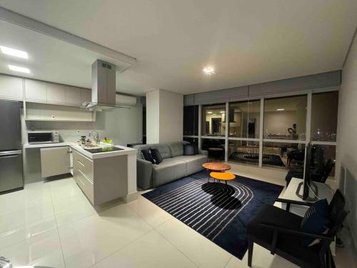 a kitchen and living room with a couch and a table at Apartamento 01 quadra da praia - LUXO Praiamar Residence in Santos