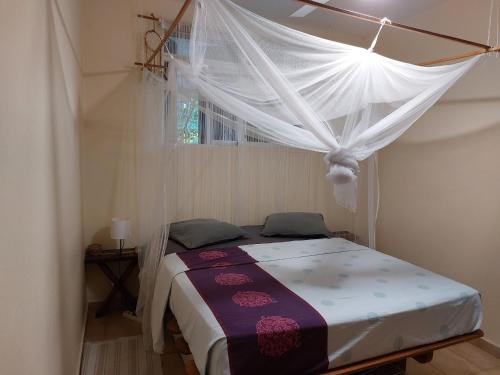 a bedroom with a bed with a mosquito net at Chambre avec terrasse vue mer in Grand-Bourg