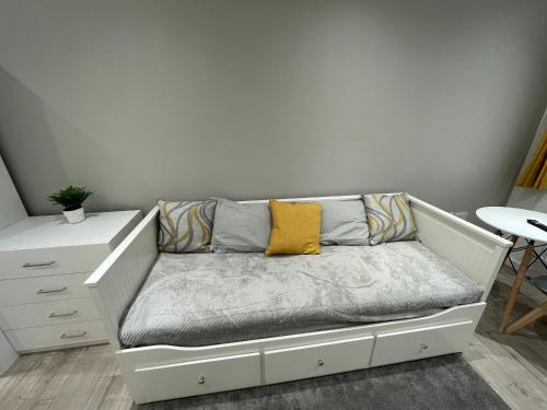 a white couch with a yellow pillow on it in a room at Garden Close Suites in Ashford