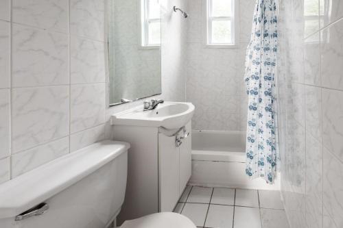 a white bathroom with a sink and a tub and a toilet at 2 bedroom apartment - 1007 in Montreal