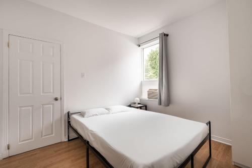 a white bedroom with a bed and a window at 2 bedroom apartment - 1007 in Montreal