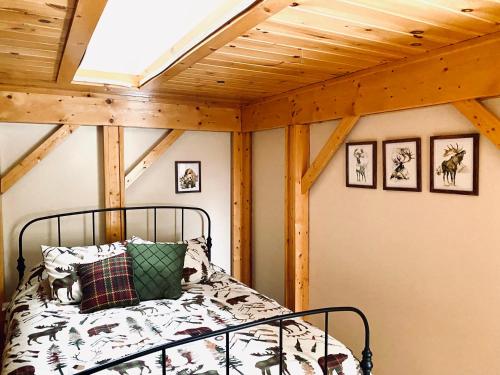 een bed in een kamer met een houten plafond bij Lazy Moose Lodge in Malone