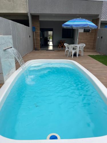 une grande piscine bleue avec une fontaine et un parasol dans l'établissement Casa Esmeralda, à Guaratuba