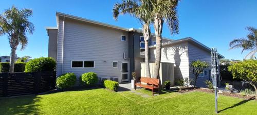 a house with palm trees and a bench in the yard at Aquila Haven in Whitianga