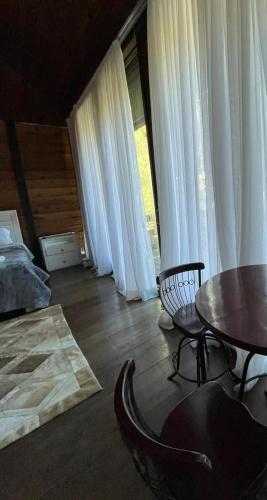 a living room with a table and chairs and white curtains at Recanto dos Sonhos Guest House in Lumiar