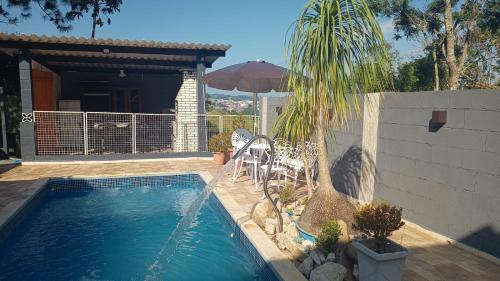 een zwembad met een palmboom naast een huis bij Recanto Itália Brasil in Biritiba-Mirim