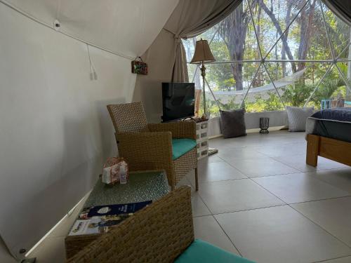 a living room with chairs and a tv and a window at Amaj Eco Lodge in Sámara