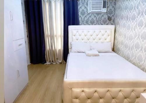 a bedroom with a white bed with a white headboard at Katas ng Japan Staycation Studio Unit in Manila
