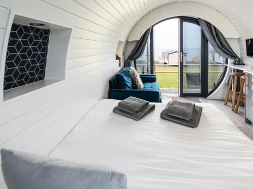 a white room with a bed and a couch at Traeth Pod - Uk46077 in Towyn