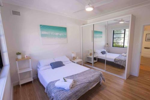 1 dormitorio con 2 camas y un espejo grande en Coastal 3 bedroom house with private oasis., en Mona Vale