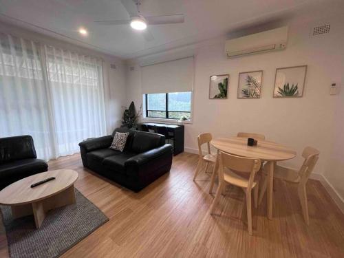 a living room with a couch and a table at Coastal 3 bedroom house with private oasis. in Mona Vale
