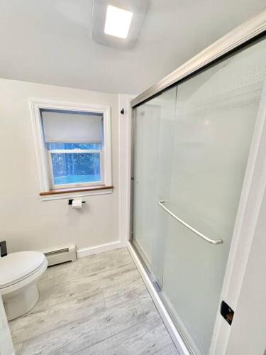a bathroom with a shower and a toilet and a window at Quiet Family Friendly Home w/ Backyard [Owls Nest] in Tremont