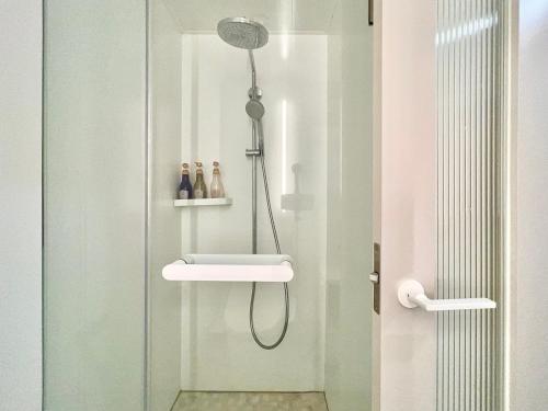 une douche dans une salle de bain avec une porte vitrée dans l'établissement 东京上野超级中心 设计师房间Yeoa 上野公园3分钟 车站1分钟 超级繁华 免费wifi 戴森吹风, à Tokyo