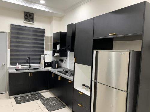 a kitchen with black cabinets and a stainless steel refrigerator at Rosevilla Homestay - 3R2B Fully Aircond WiFi in Bandar Puncak Alam