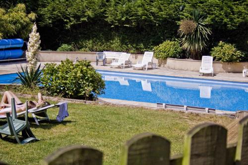 a person sitting in lawn chairs next to a swimming pool at Domaine de Keravel in Plouha
