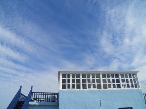 a blue building with a cloudy sky in the background at La Maison des Artistes in Essaouira