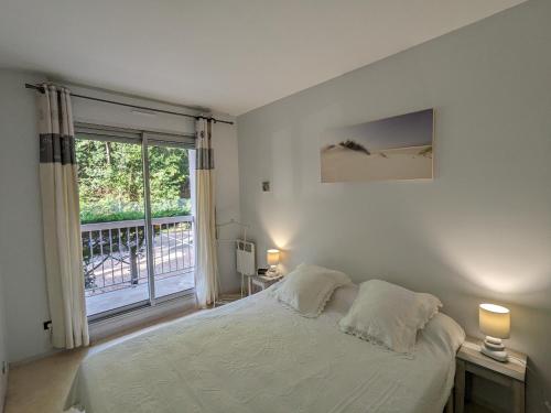 Dormitorio blanco con cama y ventana grande en Appartement Arcachon, 3 pièces, 4 personnes - FR-1-420-34, en Arcachon