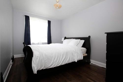 a bedroom with a bed with white sheets and a window at Cozy Airport Beauty in Winnipeg