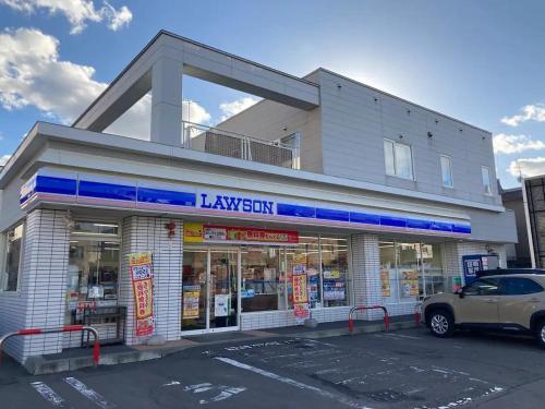 a building with a car parked in a parking lot at HS平岸 HSHiraghishi in Minami-jūichijō