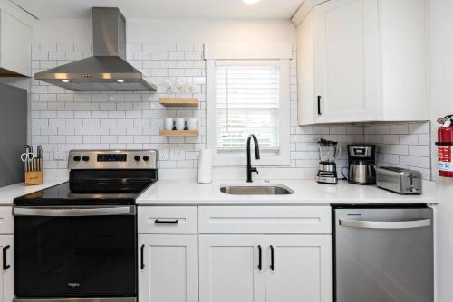 a kitchen with white cabinets and a black stove top oven at Ocean Lofts in the Vibe #2 - 5 min walk to beach in Virginia Beach