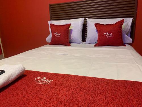 a bed with red and white pillows on it at Hotel picasso in Piura