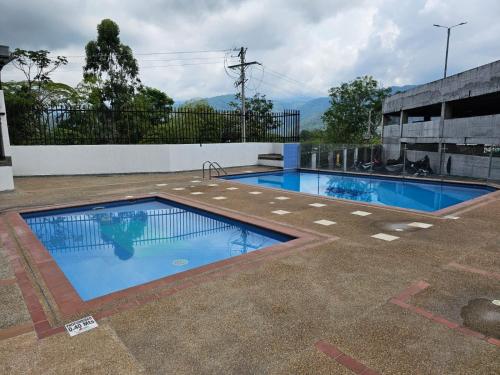 two swimming pools in a building with mountains in the background at OroNegroApartaHoteles Espectacular Apartaestudio Amoblado Armenia, Quindio in Armenia