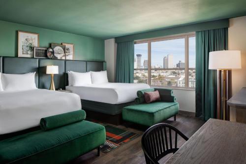 a hotel room with two beds and a green couch at Hotel Tonnelle New Orleans, a Tribute Portfolio Hotel in New Orleans