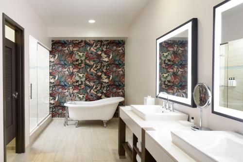 a bathroom with two sinks and a bath tub and a wall mural at Hotel Tonnelle New Orleans, a Tribute Portfolio Hotel in New Orleans