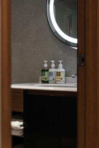 a bathroom sink with two bottles of soap and a mirror at Hotel Euphemia in Taichung