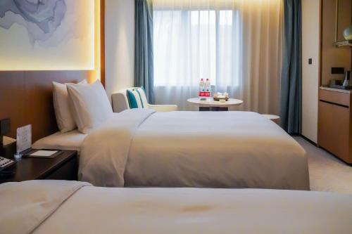 a hotel room with two beds and a table at Foreign Trade Centre C&D Hotel,Fuzhou in Fuzhou