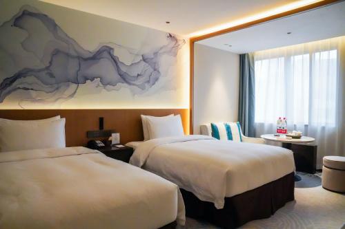 a hotel room with two beds and a painting on the wall at Foreign Trade Centre C&D Hotel,Fuzhou in Fuzhou