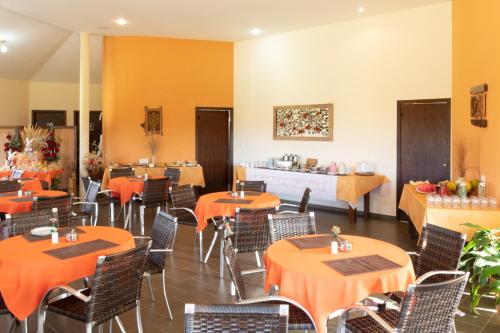 a dining room with orange tables and chairs at Pousada Além das Formas in Carrancas