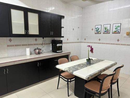 una cocina con armarios negros, mesa y sillas en ~Big House UITM Hospital 11 Pax~, en Shah Alam