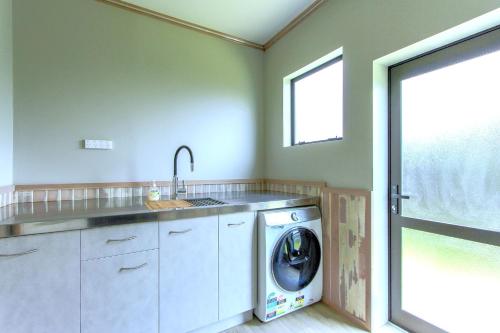 a laundry room with a washing machine and a window at Spacious retreat with Mountain View in Rotorua