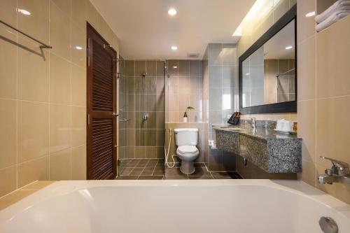 a bathroom with a tub and a toilet and a sink at Hotel J Pattaya - SHA Extra Plus in Pattaya