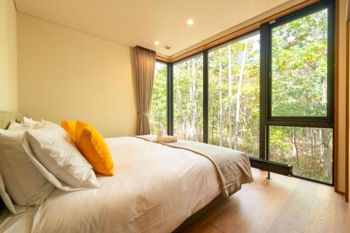 a bedroom with a white bed and large windows at Yuzen in Kutchan