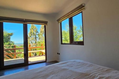 een slaapkamer met een bed en grote ramen bij Cabaña en Puerto Varas, Chile. in Puerto Varas